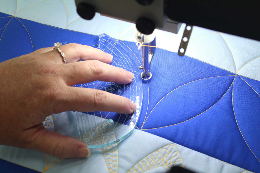 User showing the precision of an arc ruler along an APQS quilting needle.
