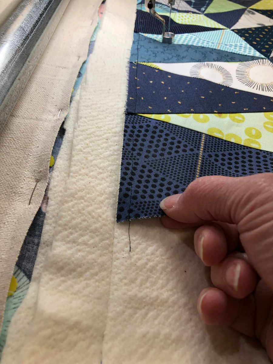 How to layer backing fabric, batting, and a quilt top together on a longarm quilting frame.