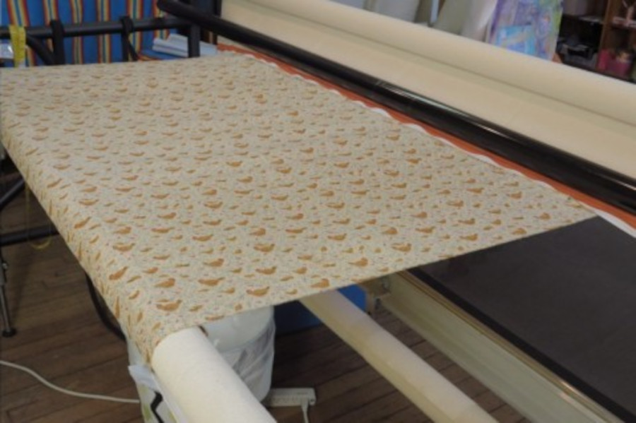 Loading a quilt on your longarm quilting machine - rolling the backing fabric up on to the quilt backing roller